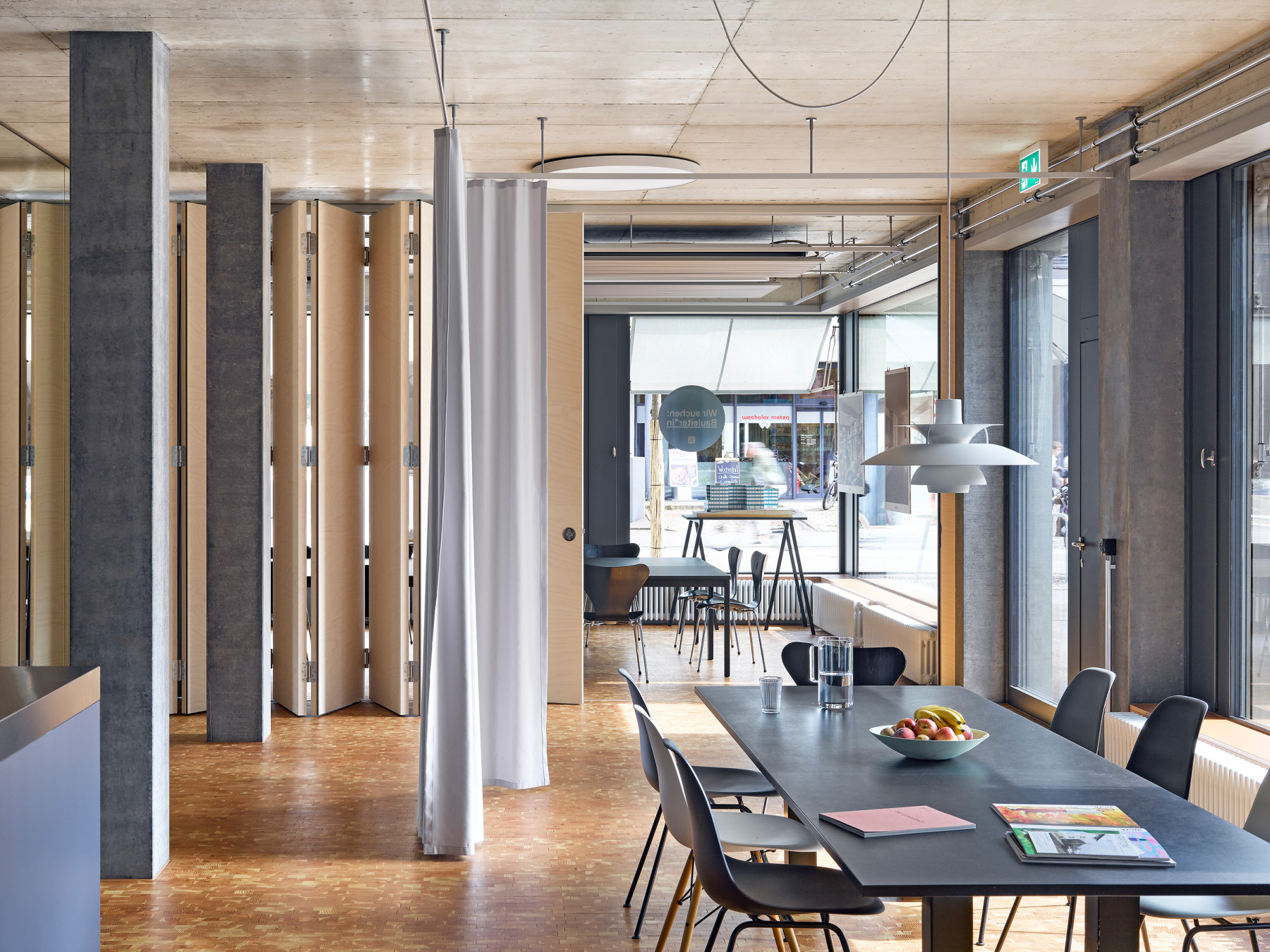 Heller Arbeitsraum im Büro von Hug Architektur mit grossem Tisch und Faltwänden